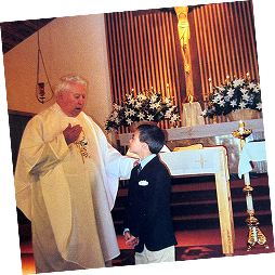 Michael Alfonso as a boy, standing with a priest in church